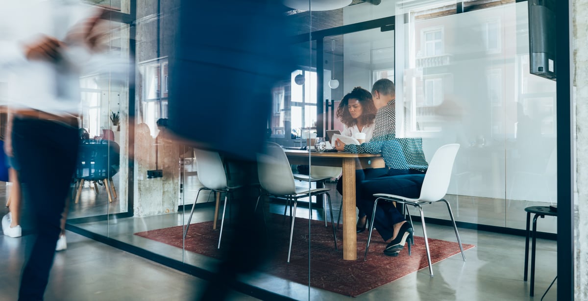 Image of two people sitting inside of a meeting room