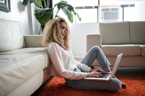 A woman sitting on the floor using a laptop